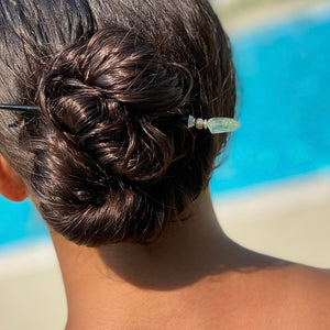 A brunette woman wears a Kira Hair Stick as she sits by the pool