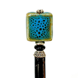 A close up of the Lark Tidal Hair Stick made from square blue raku fired ceramic beads.