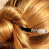 A blonde messy bun is held up by the Luna Tidal Hair Stick made from Rainbow Moonstone nugget beads.