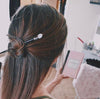 A brunette millennial woman wears a topknot using the Luna Tidal Hair Stick made from Rainbow Moonstone nugget beads.
