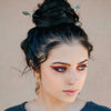 A brunette wiman wears two A close up of the Malia Tidal Hair Stick made from gray Labradorite stone beads.