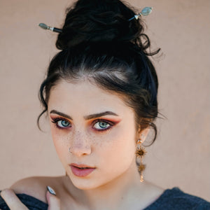 A brunette woman wears one A close up of the Malia Tidal Hair Stick made from gray Labradorite stone beads.