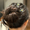 A brunette woman wears two of the Mariposa Hair Sticks made from cloisonne butterfly beads