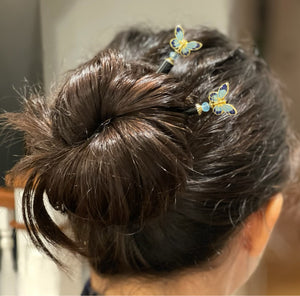 A brunette woman wears two of the Mariposa Hair Sticks made from cloisonne butterfly beads