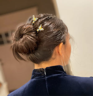 A brunette woman wears two  of the Mariposa Hair Sticks made from cloisonne butterfly beads