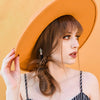 A woman wearing an orange hat and one Marley Hair stick