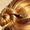 A blond woman wearing one of the Marley Tidal Hair Sticks made from iridescent blue glass beads.