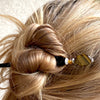 A woman wears one of our Nisha hair stick made from Tiger's Eye stone.