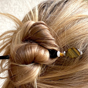 A woman wears one of our Nisha hair stick made from Tiger's Eye stone.