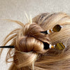 A woman wears two of our Nisha hair stick made from Tiger's Eye stone.