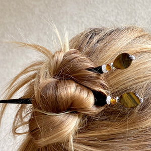 A woman wears two of our Nisha hair stick made from Tiger's Eye stone.