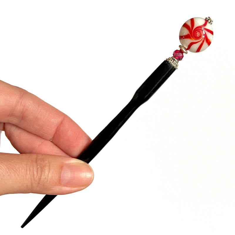 A close up of our Noelle Hair Stick made from a glass bead that looks like peppermint candy.