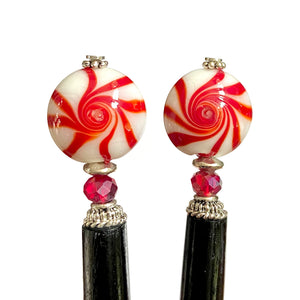 A close up of two of our Noelle Hair Sticks made from glass beads that looks like peppermint candy.