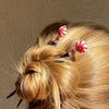 A woman wears two of our Noelle Hair Stick made from a glass bead that looks like peppermint candy.