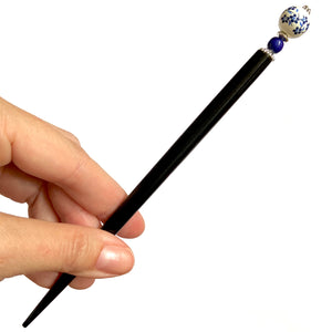 The large size of the Nora Tidal Hair Stick made from blue flowered white ceramic beads.