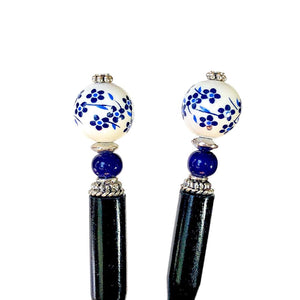 Two of the Nora Tidal Hair Sticks made from blue flowered white ceramic beads.