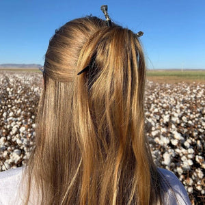 A woman wears two Palmer Hair Sticks in her half-up hairstyle.