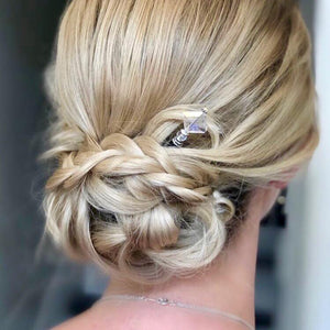 A blonde woman wears a bridal hairstyle using the Penelope Tidal Hair Stick made from iridescent clear glass beads.