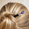A woman wears a hair bun with a Petra Tidal Hair Stick made with purple jasper stone beads.