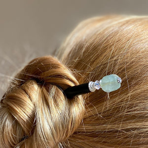 A blonde woman wearing one  of our Peyton Tidal hair Sticks made from green Kyanite stone