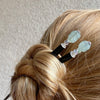 A woman wearing two  of our Peyton Tidal hair Sticks made from green Kyanite stone