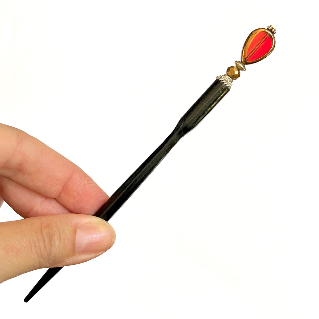A full picture of our of our Reina Hair Stick made from a red Czech glass bead with bronze edging.