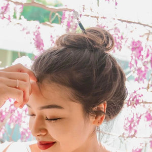 A woman wears one of our Riley Hair Sticks made from rose quartz stone.