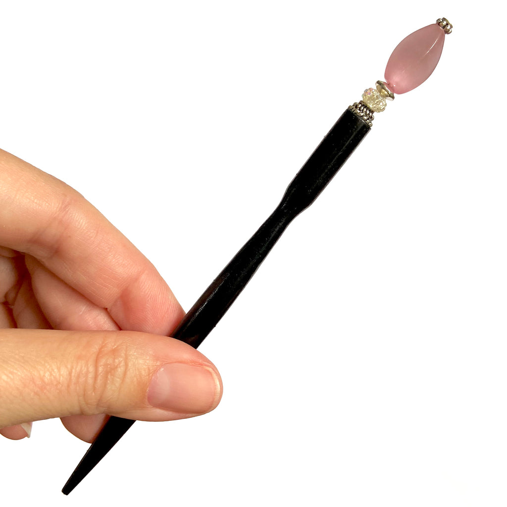 A full shot of the Roxy Tidal Hair Stick made of pink cat's eye glass.