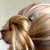 A blonde woman wearing one of our Skye Hair Stick made from an aquamarine nugget.