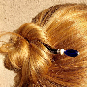 A woman wears a messy bun using the Stella Tidal Hair Stick made from cobalt blue glass beads.