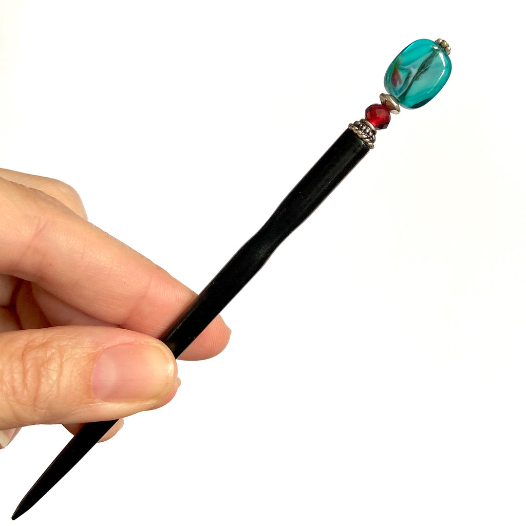 A full view of the Zara Hair Stick made from teal blue and red swirl Czech glass beads.