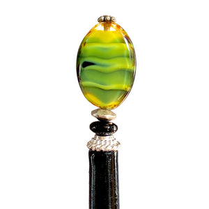 a close up of our Kaja Hair Stick made from green swirl Czech glass beads