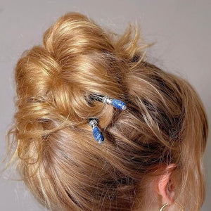 A blonde woman wears two Chloe Tidal Hair Sticks in her hair bun.