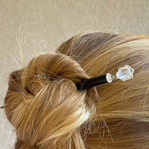 A blonde woman wears one of the Nicole Tidal Hair Stick made with an iridescent clear square bead and crystal accent. 
