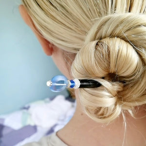 A blonde woman wears a Sapphire blue glass "Sydney" hair stick in her hairbun