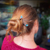 A brunette woman wears a hair bun with two Zara Tidal Hair Sticks.