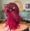 A pink haired woman wears a Freedom Tidal Hair Stick made from a silver peace sign and denim-colored accent bead