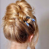 A blonde woman wears two Chloe Tidal Hair Sticks in her hair bun. 
